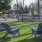 a couple of blue chairs in a grassy area with trees and a building in the background