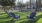 a couple of blue chairs in a grassy area with trees and a building in the background